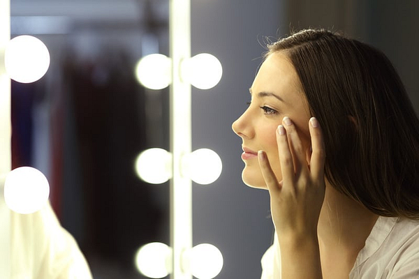 Side view portrait of a single woman checking for wrinkles looking at a make up mirror